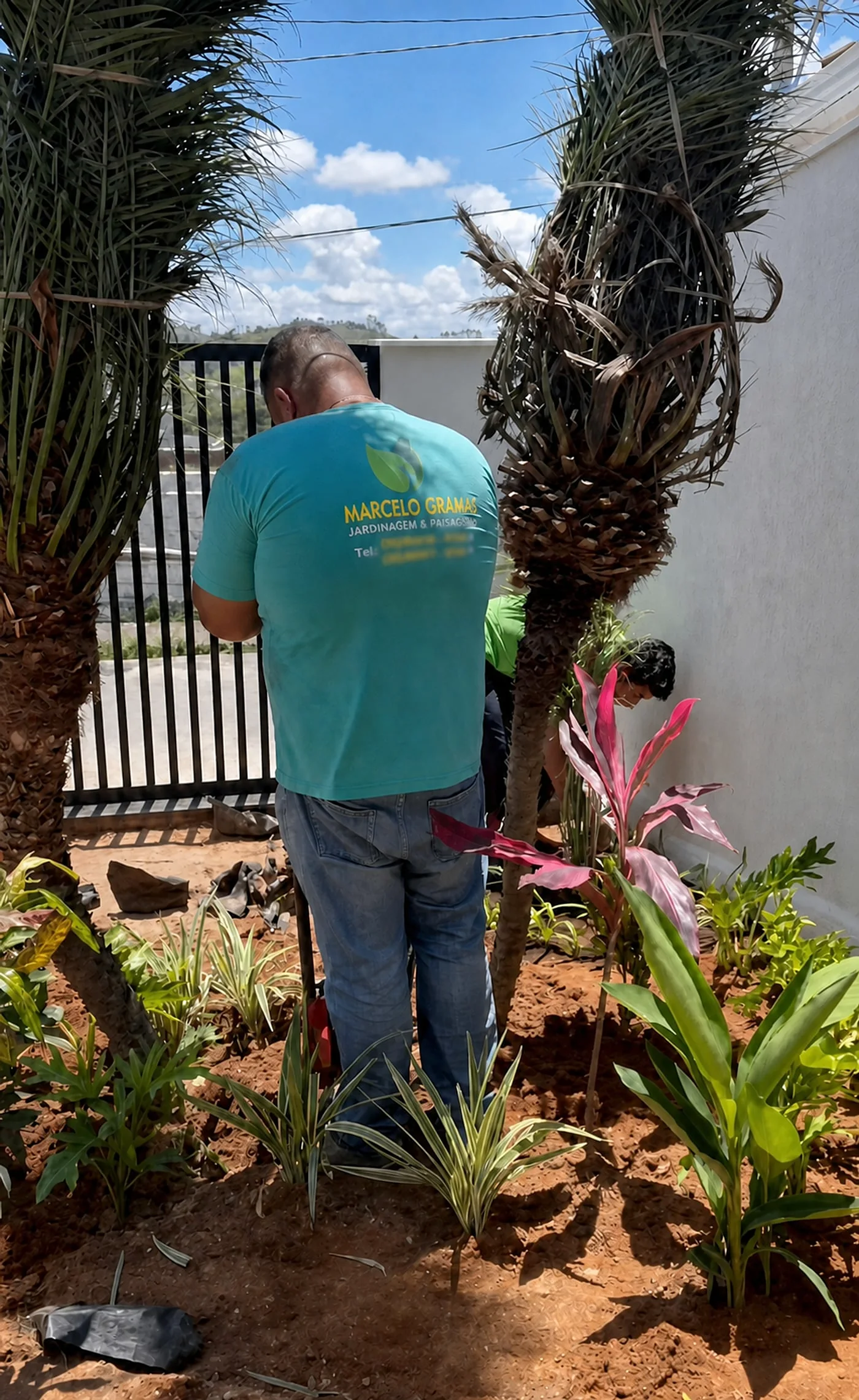 Colaborador da equipe própria, uniformizado, executando plantio junto ao portão