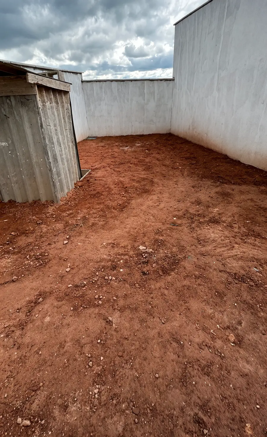 Antes: quintal murado de terra batida, sem grama, com um depósito de metal ao fundo