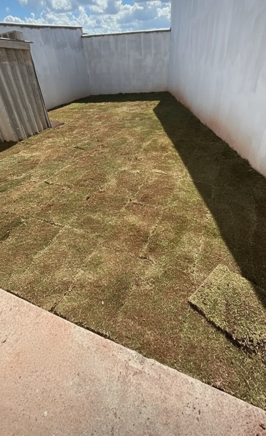 Depois: o mesmo quintal com a grama recém-instalada em placas até os muros