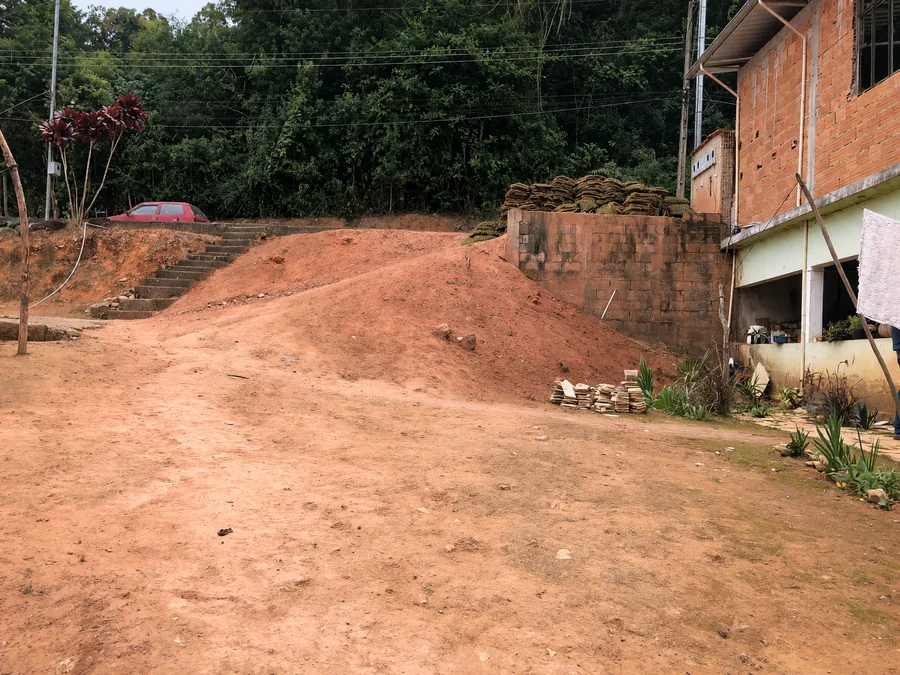 Antes: terreno em declive de terra vermelha exposta, sem cobertura
