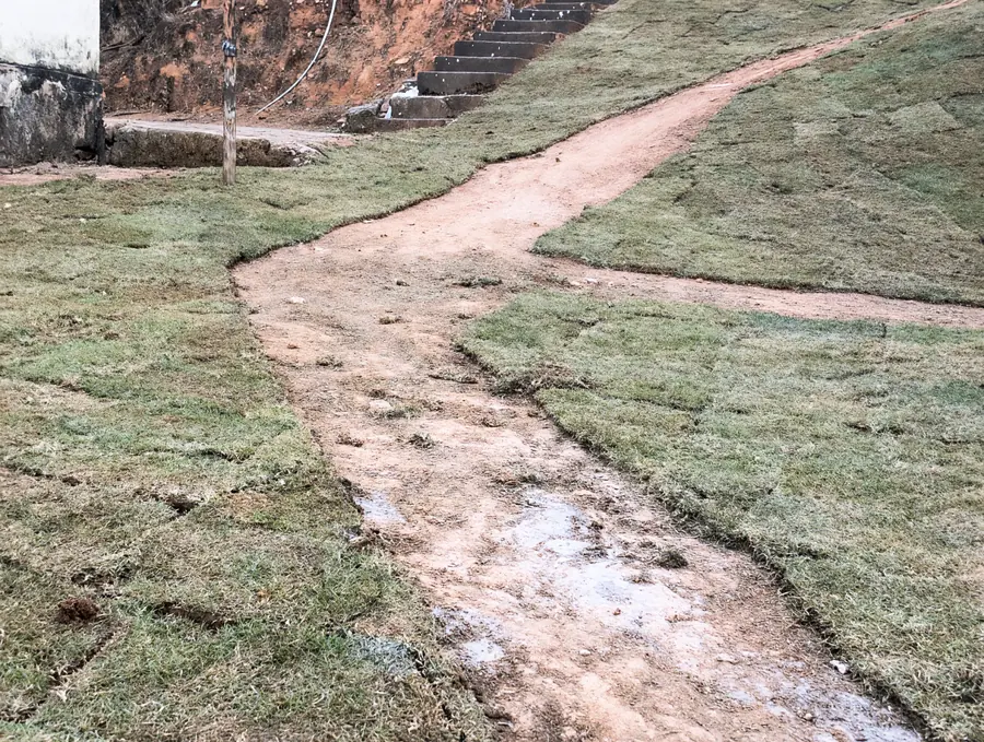 Depois: talude coberto de grama em placas, com um caminho de terra entre os gramados